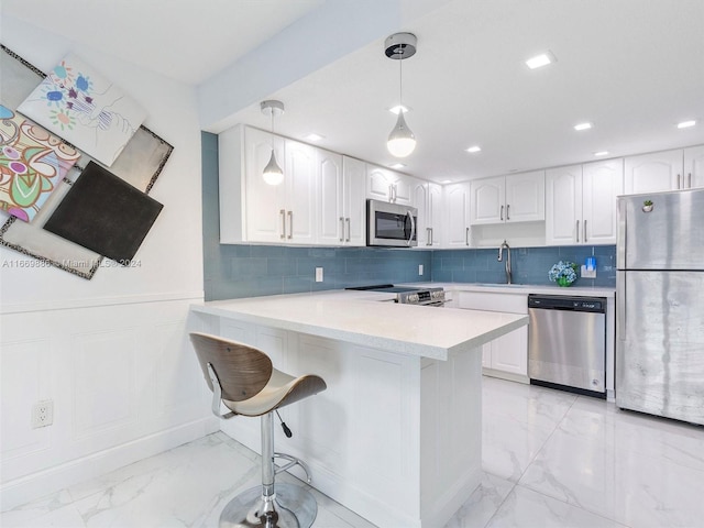 kitchen featuring white cabinetry, kitchen peninsula, appliances with stainless steel finishes, and decorative light fixtures