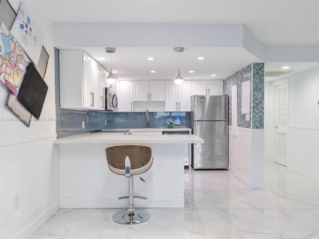 kitchen featuring appliances with stainless steel finishes, white cabinetry, kitchen peninsula, pendant lighting, and a kitchen bar