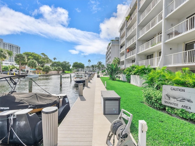 view of dock with a water view, a yard, and a balcony