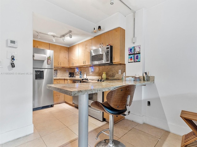 kitchen with appliances with stainless steel finishes, a breakfast bar, backsplash, kitchen peninsula, and light tile patterned floors