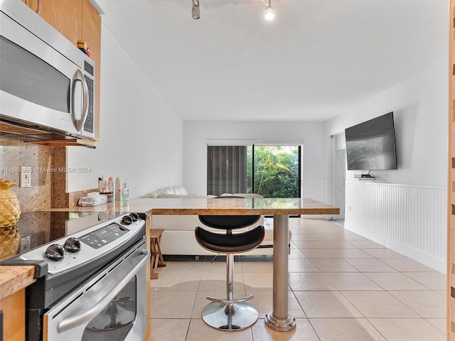 kitchen with kitchen peninsula, light tile patterned flooring, and stainless steel appliances