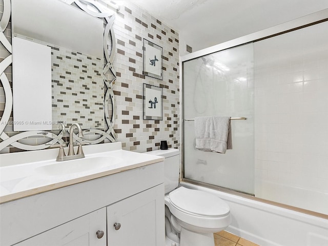 full bathroom featuring tile walls, tile patterned flooring, shower / bath combination with glass door, vanity, and toilet