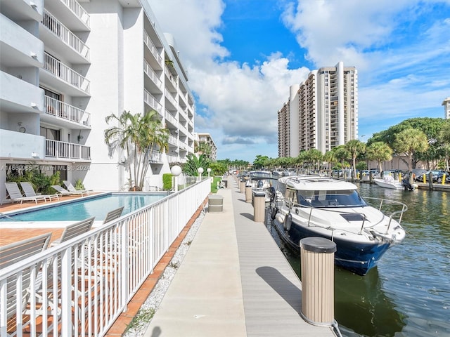 dock area featuring a community pool, a balcony, and a water view