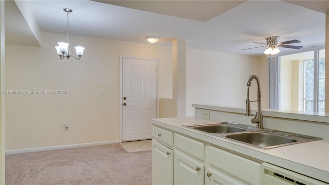 kitchen with white dishwasher, sink, decorative light fixtures, light carpet, and ceiling fan with notable chandelier