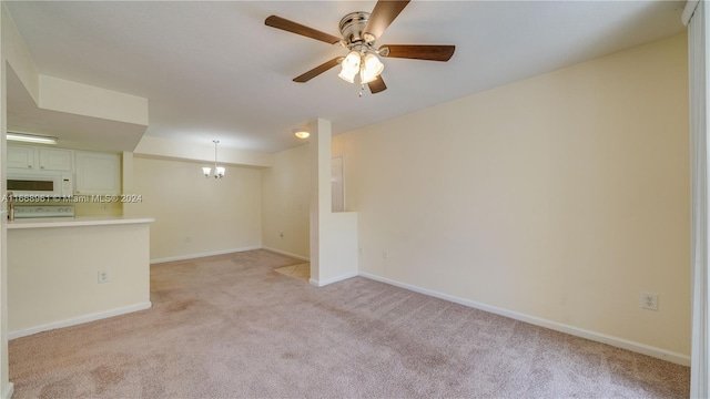 carpeted spare room with ceiling fan with notable chandelier