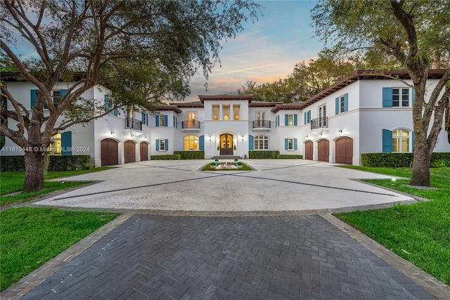 mediterranean / spanish home with a balcony, a garage, and a yard