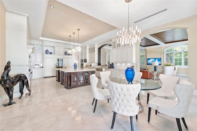 dining space with a raised ceiling, ornamental molding, and a chandelier