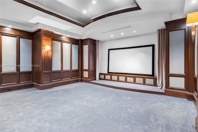 carpeted cinema room featuring a raised ceiling and crown molding