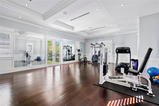 workout area featuring a raised ceiling, ornamental molding, dark wood-type flooring, and french doors