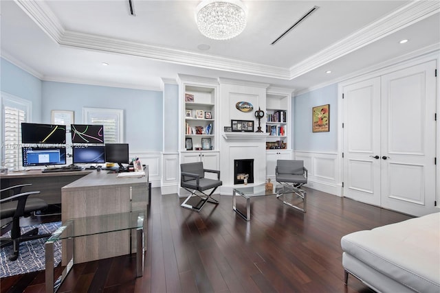 office space featuring a tray ceiling, a chandelier, dark hardwood / wood-style flooring, ornamental molding, and built in features