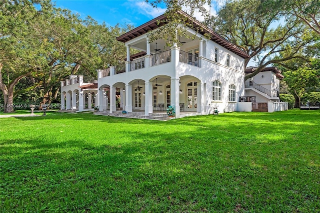 rear view of property featuring a balcony and a yard