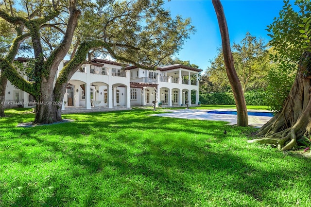 back of property featuring a lawn and a balcony