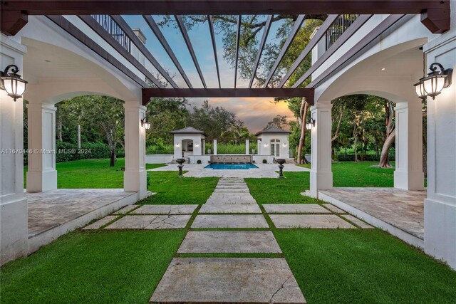 yard at dusk featuring a balcony and a patio area