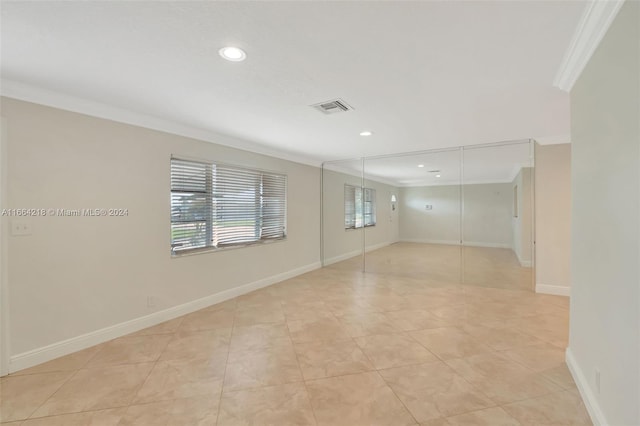 tiled spare room featuring crown molding