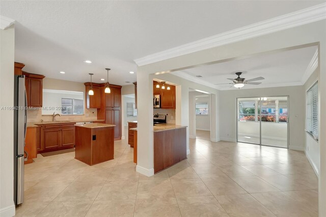 kitchen featuring brown cabinets, stainless steel appliances, backsplash, a sink, and a kitchen island
