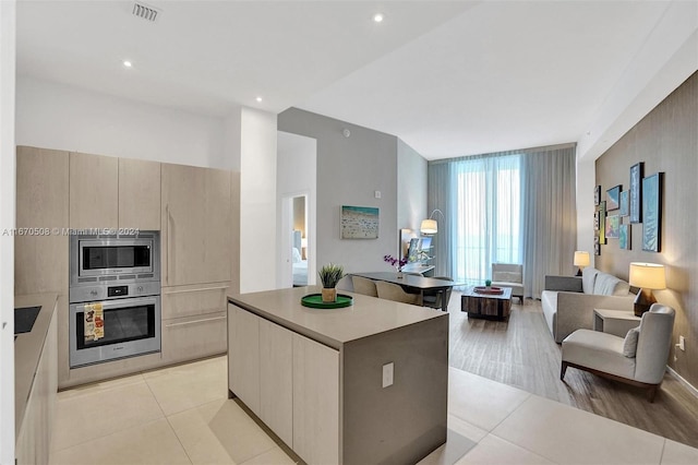 kitchen with light brown cabinetry, light hardwood / wood-style flooring, stainless steel appliances, and a kitchen island