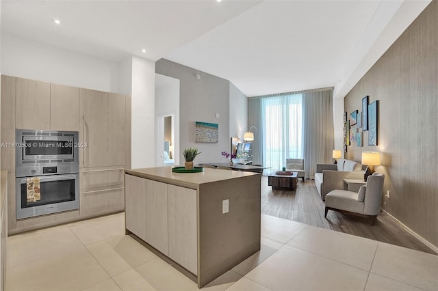 kitchen with light hardwood / wood-style flooring, stainless steel double oven, light brown cabinetry, and a kitchen island