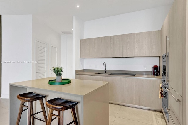 kitchen with light tile patterned flooring, a breakfast bar area, sink, and a center island