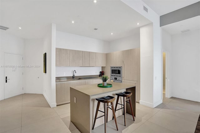 kitchen featuring sink, a breakfast bar, light tile patterned floors, and a kitchen island