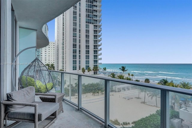 balcony with a water view and a view of the beach