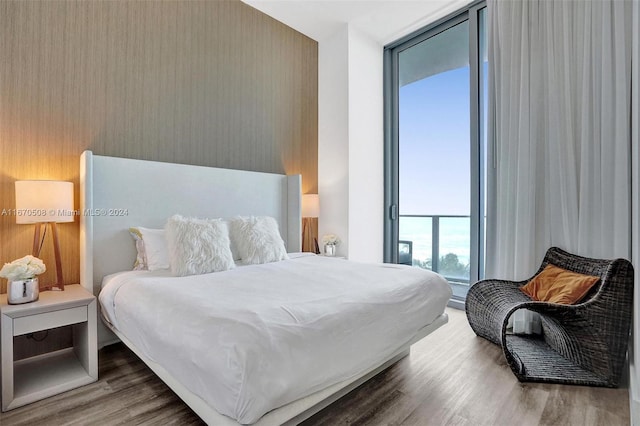 bedroom with wood-type flooring and expansive windows