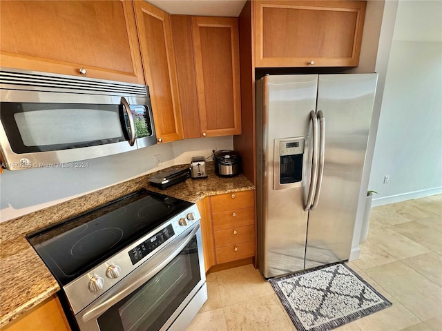 kitchen with stainless steel appliances, light stone counters, and light tile patterned floors