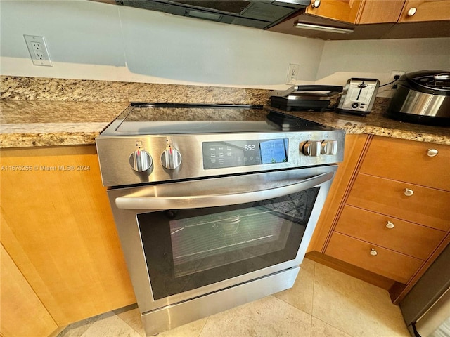 room details featuring stainless steel range with electric stovetop and light tile patterned flooring