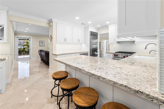 kitchen with premium appliances, a kitchen bar, and white cabinetry