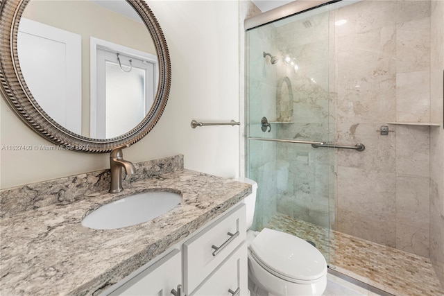 bathroom featuring vanity, toilet, and a shower with door