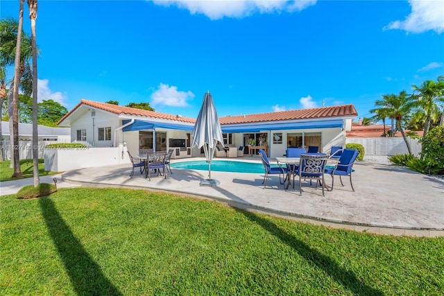 rear view of property featuring a fenced in pool, a patio area, and a yard