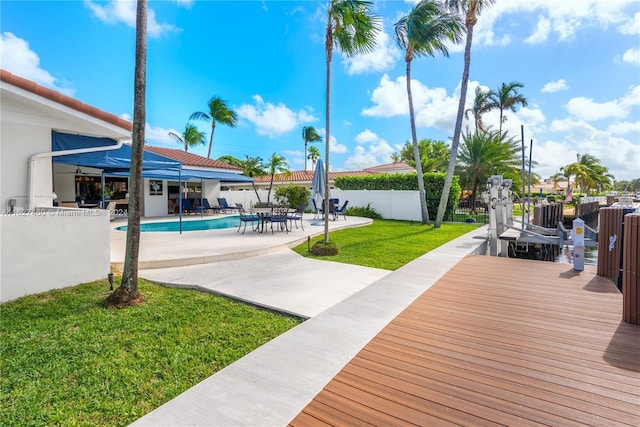 deck featuring a fenced in pool, a patio area, and a lawn