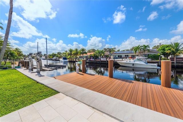 view of dock with a lawn and a water view