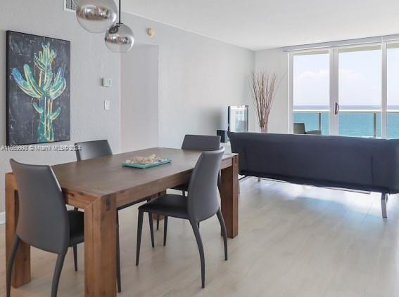 dining space featuring light wood-type flooring and a water view