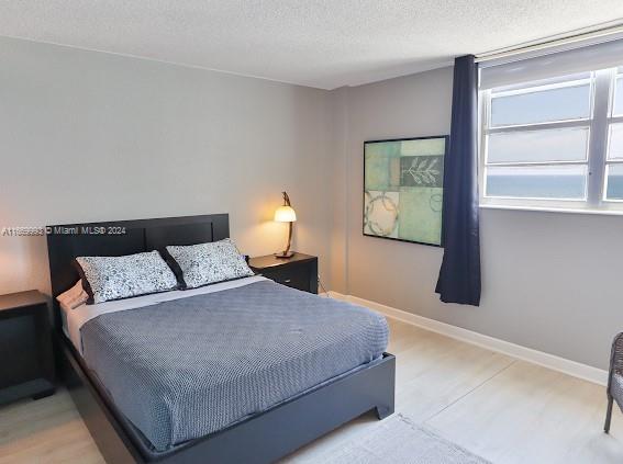 bedroom with a textured ceiling and light hardwood / wood-style floors