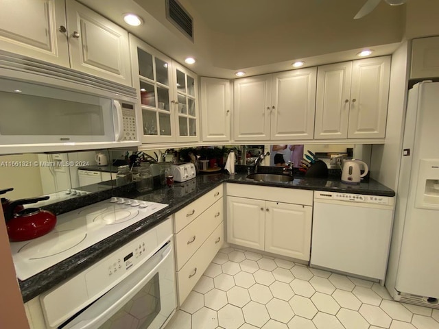 kitchen featuring dark stone counters, white appliances, white cabinetry, and sink