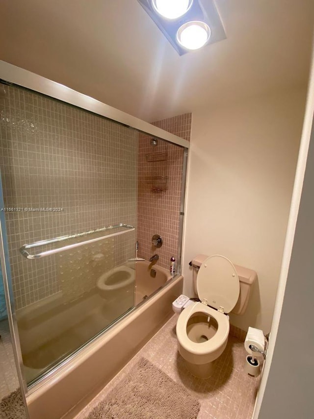 bathroom featuring bath / shower combo with glass door and toilet