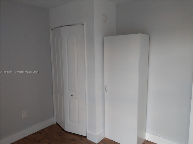 unfurnished bedroom with a closet and dark hardwood / wood-style flooring