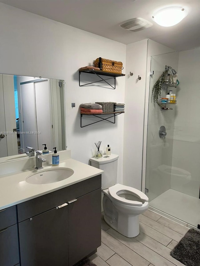 bathroom featuring hardwood / wood-style flooring, vanity, toilet, and a shower with shower door