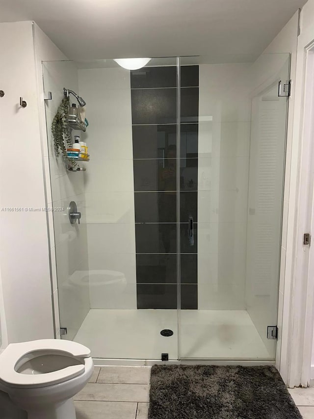 bathroom featuring toilet, tile patterned floors, and an enclosed shower