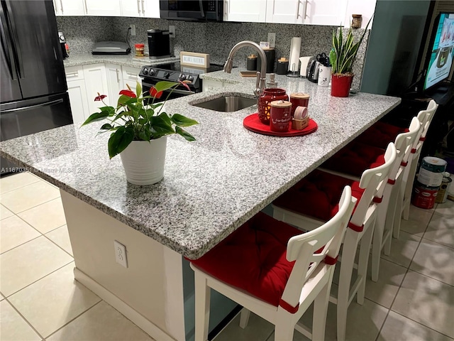 kitchen with white cabinets, range with electric stovetop, black fridge, and kitchen peninsula