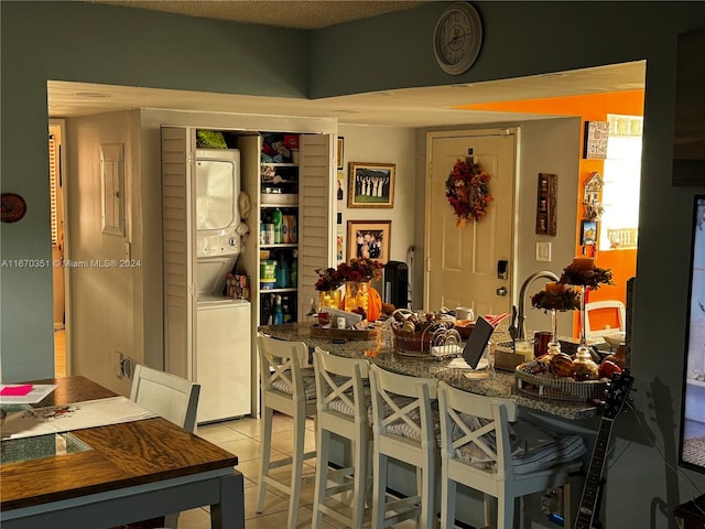 tiled dining area featuring stacked washer and clothes dryer