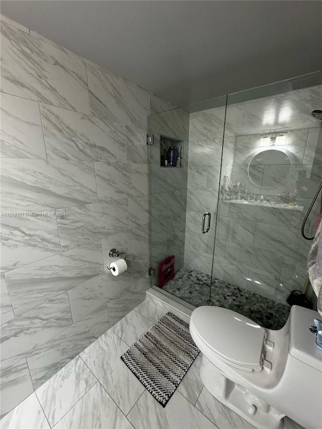 bathroom featuring toilet, tile walls, and a shower with door