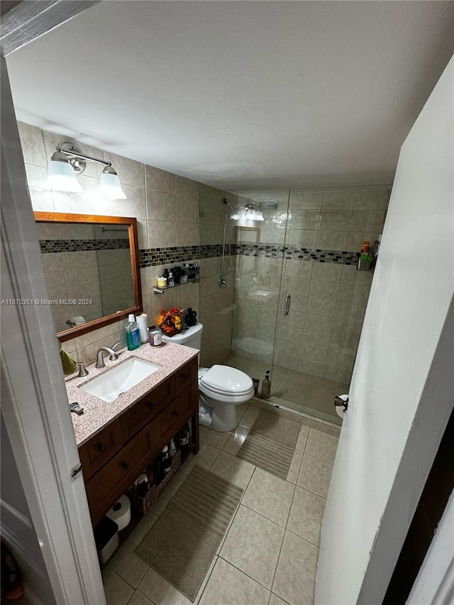 bathroom with toilet, vanity, tile walls, and tile patterned floors