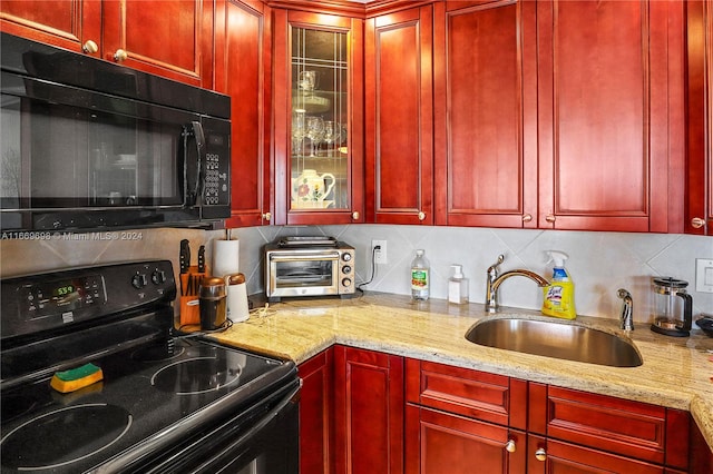 kitchen featuring light stone countertops, black appliances, backsplash, and sink