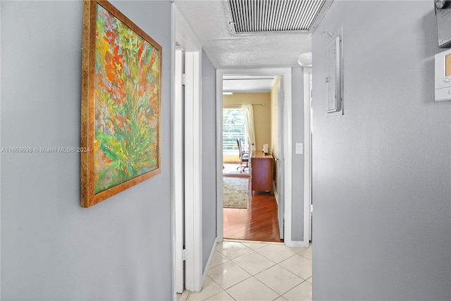 hallway featuring a textured ceiling and light tile patterned floors