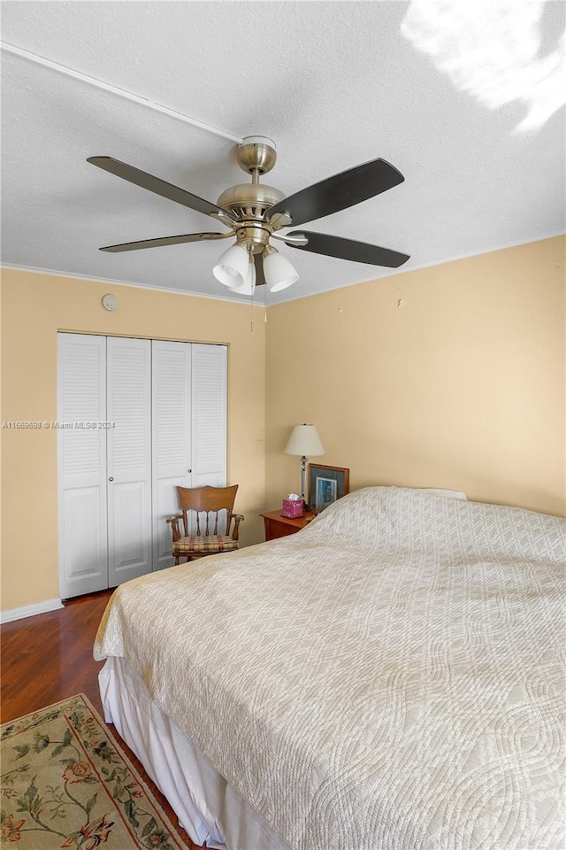 bedroom with a closet, ceiling fan, hardwood / wood-style flooring, and a textured ceiling