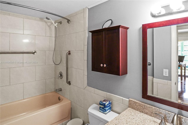 full bathroom featuring tile walls, vanity, toilet, and tiled shower / bath