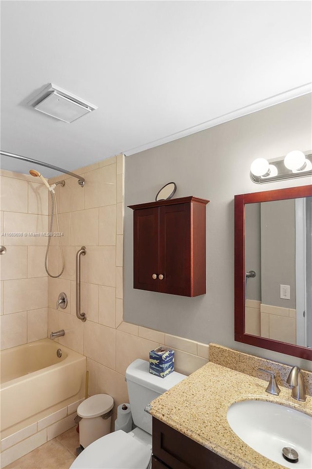 full bathroom featuring tile walls, tiled shower / bath combo, tile patterned floors, vanity, and toilet