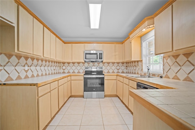 kitchen with light brown cabinetry, appliances with stainless steel finishes, backsplash, and tile countertops