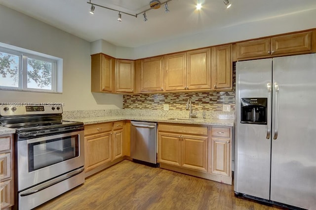 kitchen with track lighting, sink, light hardwood / wood-style flooring, backsplash, and appliances with stainless steel finishes